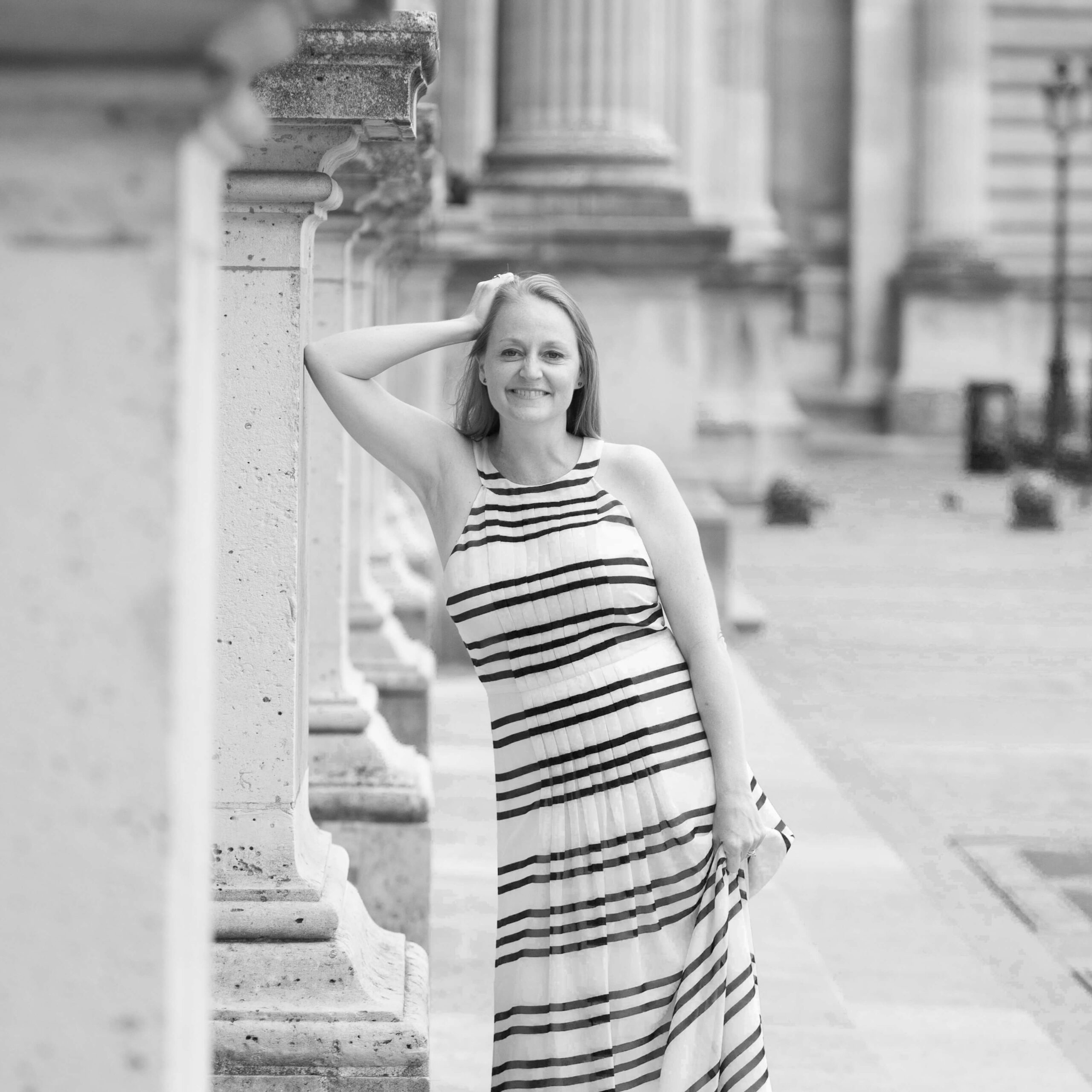 tanya quinn leading against columns in blue and white striped dress - founder of small actions greater good and COO of truby achievements